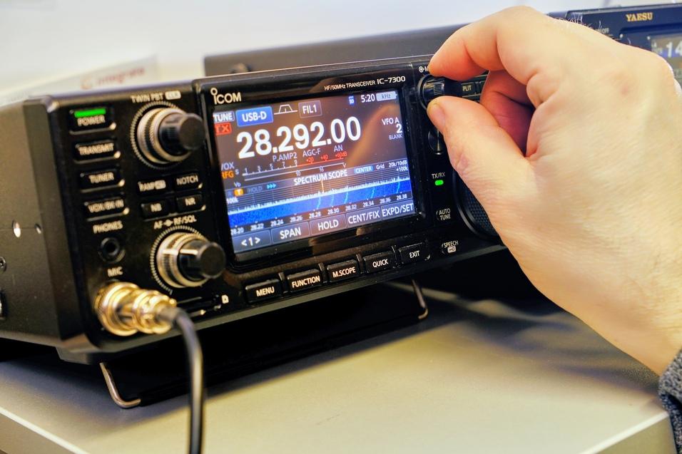 ein Kurzwellenfunkgerät ICOM IC-7300 ist zu sehen, Die Frequenz 28.292 kHz ist im Display zu sehen, die rechte Hand eines OMs dreht ein Einstellrad
