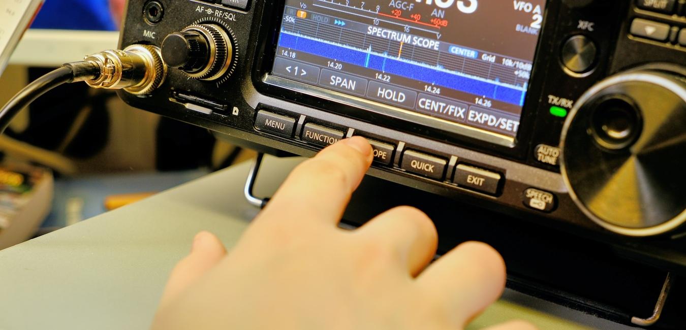 Kurzwellen Funkgerät, auf dem Display ist die Frequenz 14.224.93 kHz zu sehen, der Zeigefinger der rechten hand drückt eine Taste