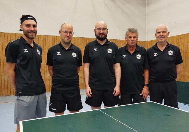 Fünf Männer in schwarzen Trikots an einer Tischtennisplatte